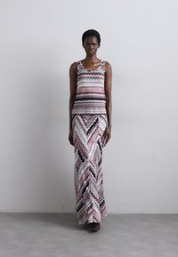 Maxi jurk en tanktop set in zigzagpatroon, met tinten van roze, wit en zwart. Gemaakt van een zachte stof, met een getailleerde bodice en een vloeiende rok.