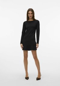 Vestido negro de manga larga con corte recto, con cuello redondo y dobladillo acampanado. Tela suave con silueta ajustada.