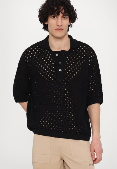 Pull noir en tricot avec un motif en maille ouverte, des manches courtes et un col côtelé. Présente une patte de boutonnage à trois boutons et une texture subtile.