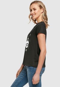 Black cotton t-shirt with a loose fit, short sleeves, and a graphic print of a face in white on the front.