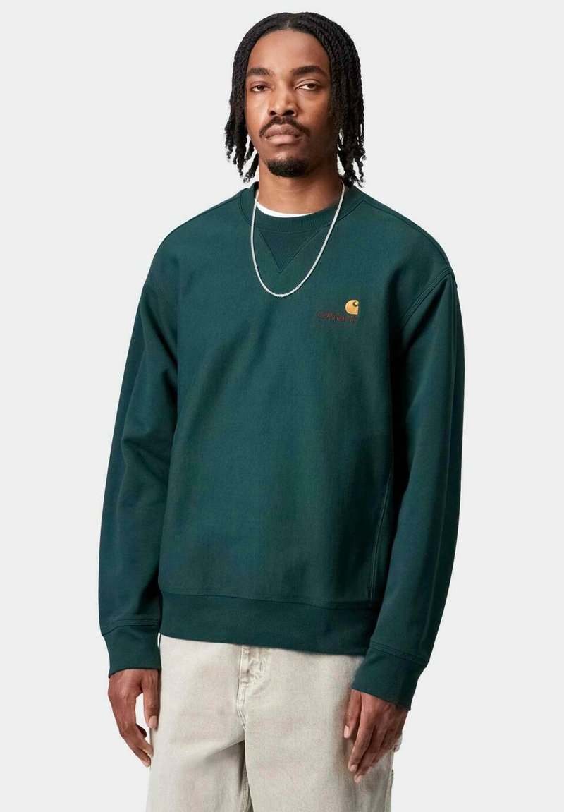 Sudadera verde oscuro de mangas largas, con cuello redondo y puños acanalados. Presenta un pequeño logo naranja en el pecho. Textura de tela suave.
