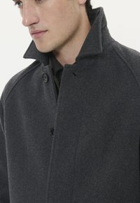 Cappotto in misto lana charcol con colletto alto, chiusura a doppio bottone e tessuto testurizzato. Design semplice e classico con vestibilità su misura.