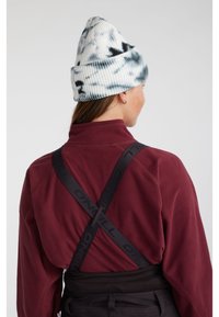 Pletiva kapa v beli barvi z modro-sivo tye-dye vzorcem. Maroon flis zgornji del z črnimi trakovi, na katerih je logotip "ONEILL". Temni hlače spodaj.