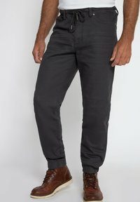 Männer Jogginghosen in Dunkelgrau aus weichem Material, ausgestattet mit einem elastischen Bund und Kordelzug, schmal zulaufenden Beinen und gerippten Bündchen.