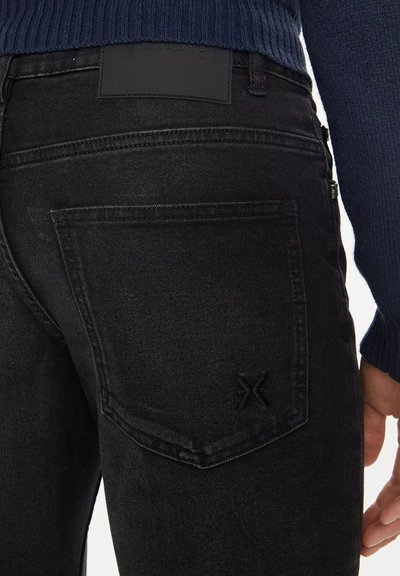 I jeans in denim nero presentano un classico design a cinque tasche, un logo in pelle sulla vita e un motivo di cucitura distintivo sulla tasca posteriore.