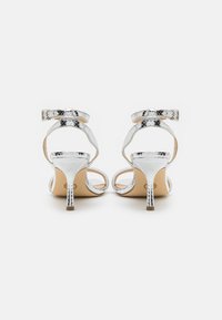 Sandale cu toc înalt din piele de șarpe argintie, cu spate deschis, curea la gleznă și toc subțire stiletto, având un finisaj texturat și un design minimalist.