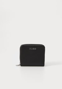 Portefeuille en cuir noir de forme rectangulaire, fermeture zippée et logo "HUGO" argenté sur le devant. Texture lisse avec un design minimaliste.