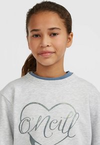 Sudadera gris claro con cuello redondeado y mangas largas, que presenta un diseño colorido de un corazón y el nombre "O'Neill" en una fuente decorativa.