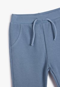 Blaue gerippte Strickhosen mit elastischem Bund und Kordelzug, ausgestattet mit Fronttaschen.