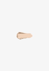 Tache de fond de teint crème beige clair avec des bords lisses et texturés sur fond blanc.