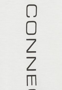 Weißes Baumwollhemd mit vertikalem schwarzen Text, der "CONNECTED" schreibt. Einfaches Design, klare Linien und glatte Textur.