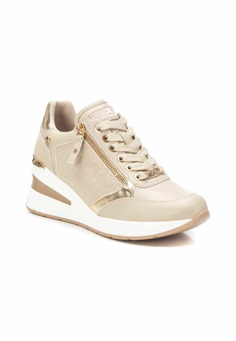 Sneaker wedge beige con accenti metallici dorati, dettagli testurizzati, chiusura con lacci sulla parte anteriore e zip decorativa. Suola bianca con fondo marrone chiaro.