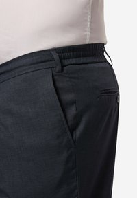 Černé kalhoty s elastickým pasem z texturované látky, s bočními kapsami a zadní kapsou na knoflík.