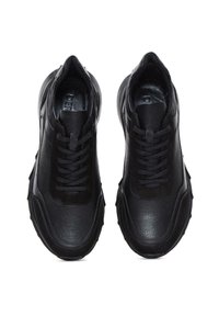 Zapatillas de cuero negro con un upper texturizado, cordones planos y una suela de goma gruesa con acentos geométricos. Sin marcas visibles.