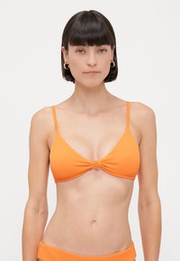 Top de biquíni laranja com nervuras, com alças finas ajustáveis e um detalhe em nó no centro. Textura suave e copas triangulares para um ajuste perfeito.