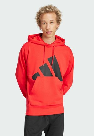 Röd hoodie med svart logotyp på framsidan. Har en känguruficka, justerbar dragsko på huvan och ribbade manchetter vid ärmar och nederkant.