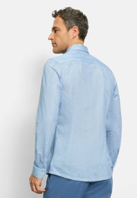 Lange mouw shirt in lichtblauwe stof met een subtiele textuur, voorzien van een klassieke kraag en knoopmanchetten. Achteraanzicht toont een rechte snit.