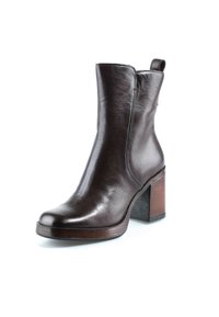Bottine en cuir marron foncé avec un bout arrondi, une languette de tirage et un talon bloc empilé sur fond blanc.