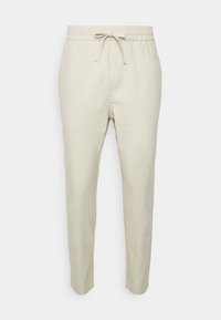 Light beige linen pants with an elastic waistband and adjustable drawstring. Features side pockets and a tapered leg design.