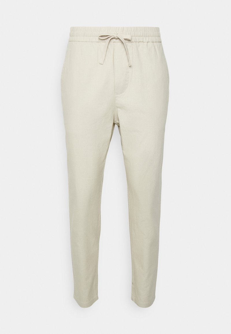 Light beige linen pants with an elastic waistband and adjustable drawstring. Features side pockets and a tapered leg design.