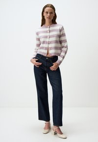 Cardigan a righe in lavanda pallido e bianco, con bottoni rotondi e un design cropped, abbinato a jeans a gamba larga in denim scuro e tacchi beige.
