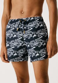 Bañador negro con un atrevido patrón gráfico en blanco y rojo de "Red Bull Racing", cintura con cordón y un material ligero.