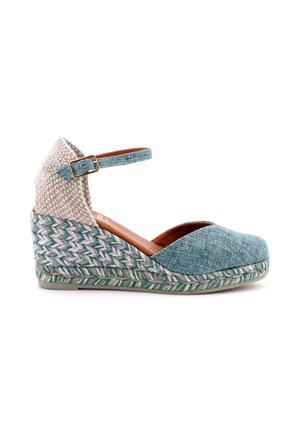 Espadrillas con zeppa con tacco intrecciato, punta in tessuto verde acqua, cinturino alla caviglia con fibbia e suola intrecciata in juta su sfondo bianco.