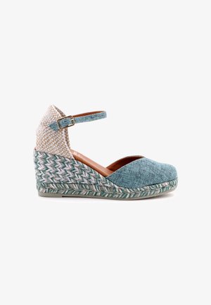 Espadrillas con zeppa con tacco intrecciato, punta in tessuto verde acqua, cinturino alla caviglia con fibbia e suola intrecciata in juta su sfondo bianco.