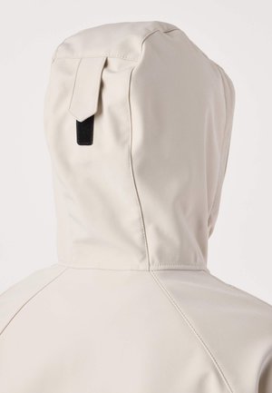 Lichtbeige gewatteerde jas met capuchon en een klein zwart lusje bovenop de capuchon, gezien van achteren.