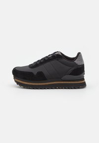 Baskets noires en matériaux suédés et synthétiques, avec un talon texturé gris, un laçage et une semelle en caoutchouc brun striée.