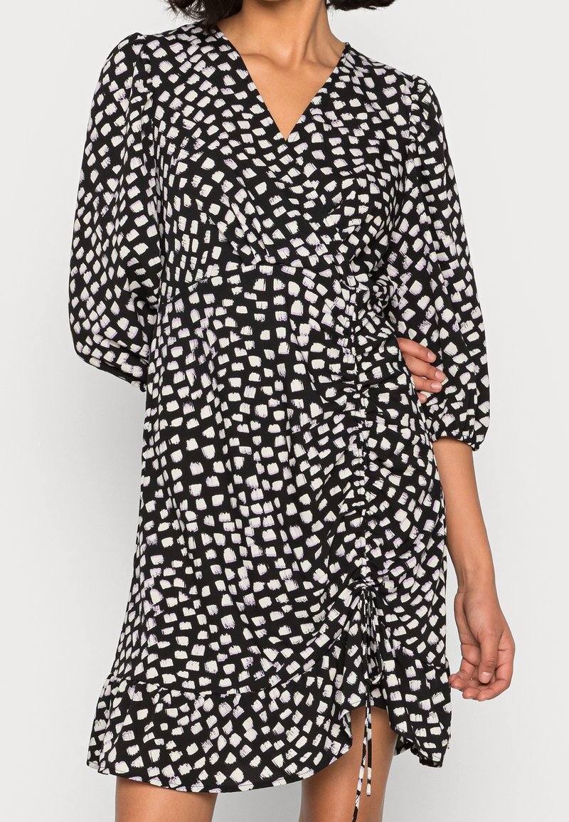 Robe noire avec motif de coups de pinceau blancs et violets clairs, col en V, manches bouffantes, détail à cordon à la taille et ourlet à volants.
