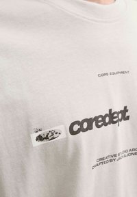 Heledhall hall t-särk, millel on must tekst "coredept." ja väike graafiline logo. Ümar kaelus, lühikesed varrukad ja pehme tekstuur.