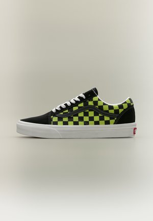 Baskets basses avec motif damier noir et jaune, lacets blancs et semelle épaisse en caoutchouc blanc, vues de profil sur un fond neutre.