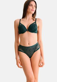 Soutien-gorge en dentelle vert foncé avec des bords festonnés et un motif floral, assorti à des culottes en dentelle avec une taille lisse.