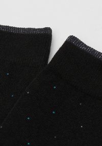 Zwarte sokken met een soepele textuur, voorzien van een geribde boord en verspreide kleine blauwe en witte stippen voor extra detail.