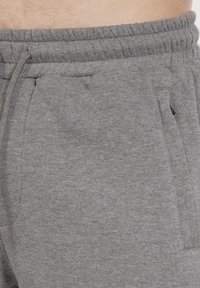 Grijze katoenmix sweatpants met een elastische tailleband, zijzakken en een zachte textuur. De stof heeft een subtiel gemêleerd patroon.