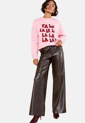Pink sweatshirt with red sequined "FA LA LA" text, paired with wide-leg brown faux leather pants and burgundy high heels.