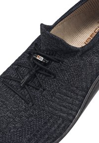 Czarne dzianinowe buty o teksturowanej powierzchni. Posiadają okrągły nosek, elastyczne sznurowadła i miękkie wnętrze. Minimalne detale metalowe.