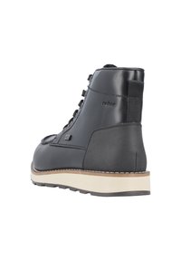 Bottine en cuir noir avec des lacets, un talon robuste et une semelle claire avec des accents de couture. Logo de la marque sur le côté.