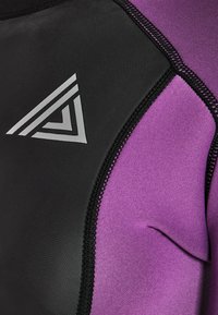 Zbliżenie na czarny i fioletowy materiał neoprenowy z czarnymi szwami oraz białym trójkątnym logo na czarnej części.