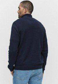 Marinblå sweatshirt med hög krage, ribbade ärmslut och nederkant. Tillverkad av ett mjukt material, med en slät yta och rena linjer.