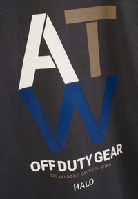 Ciemnoszara tkanina z wyrazistym graficznym napisem: "AT W OFF DUTY GEAR" w białym, brązowym i niebieskim kolorze. Materiał wydaje się gładki i miękki.