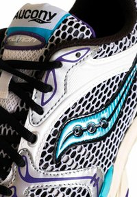 Sneaker bianco e nero con tomaia in rete, accenti turchesi e dettagli viola. Presenta lacci neri e un'etichetta con il marchio sulla linguetta.