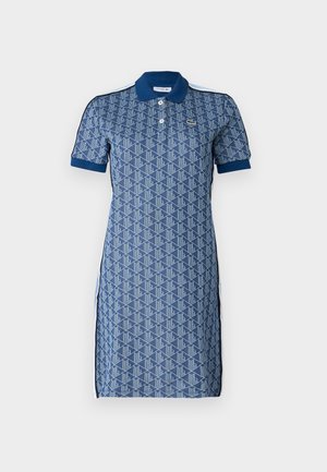 Abito polo con un motivo geometrico blu, maniche corte, scollatura con bottoni e colletto blu a contrasto. Fessure laterali e dettagli bianchi.