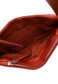 Innerraum einer roten Lederhandtasche mit glatter Textur, ausgestattet mit einem Reißverschlussfach und zwei Steckfächern auf einem weichen Stofffutter.