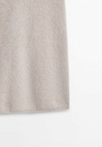 Lys beige strikket sweater med en blød og fluffy tekstur, der har en afslappet pasform, rund halsudskæring og diskrete detaljeringer i kanten.