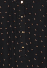 Černý látkový top s drobnými hnědými tečkami, s button placket se pěti zlatými knoflíky a kulatým výstřihem. Měkká textura.