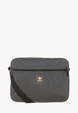 Grå tyg budväska med en dragkedjeförsedd framficka, justerbar svart axelrem och guld Adidas logopanel. Rektangulär design.