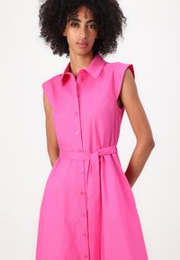 Rochie cu maneci scurte, cu nasturi, din bumbac roz vibrant, cu talie strânsă și curea din același material, dotată cu guler și croi lejer.