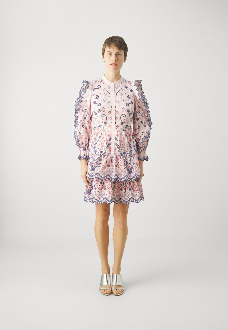 Rotes Blumenmusterkleid mit blauen Akzenten, Rüschen an den Ärmeln, gewelltem Saum und Knopfleiste. Kombiniert mit silbernen, offenen Mules.
